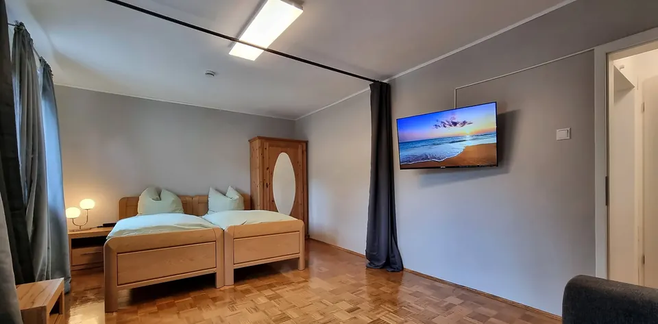Helles Schlafzimmer mit Holzbetten, Kleiderschrank und Fernseher