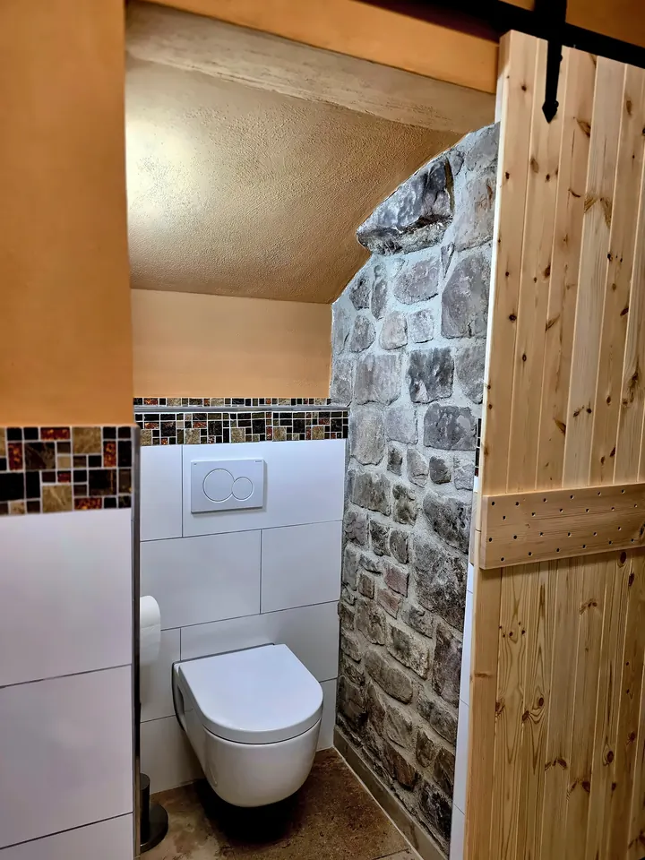 WC neben einer Wand aus Naturstein