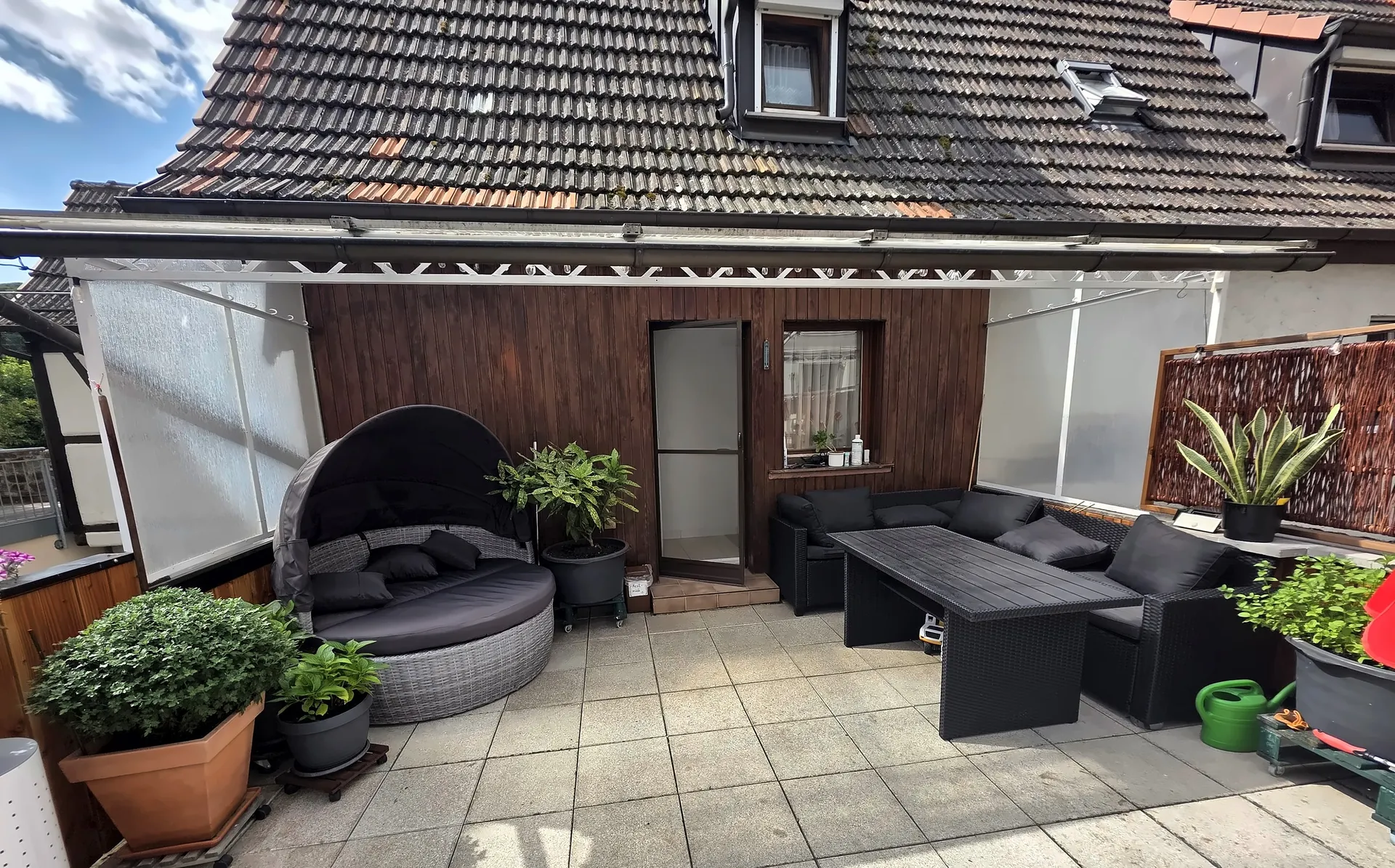 Terrasse mit Sonneninsel, Pflanzen und Sitzgruppe vor der Holzfassade